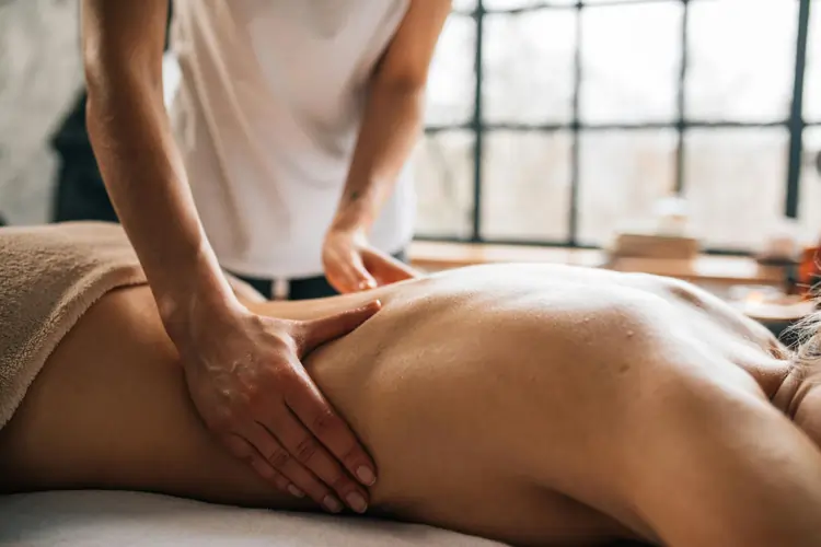 Massaggio benessere praticato a una donna sdraiata su un lettino di un un centro estetico | QuBox